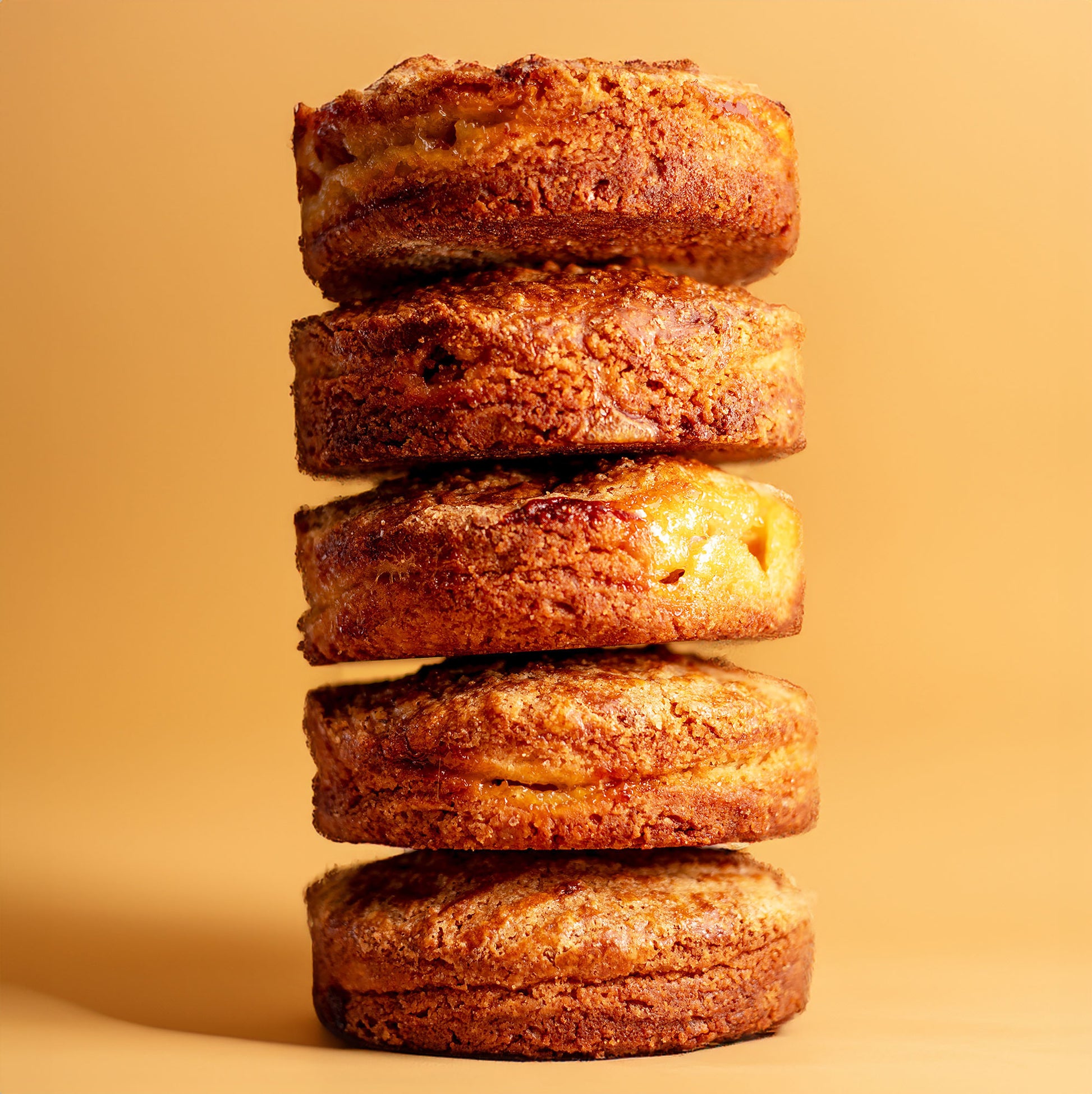 Image of stack of 5 Pear Gâteau Breton pastries on a light orange background.