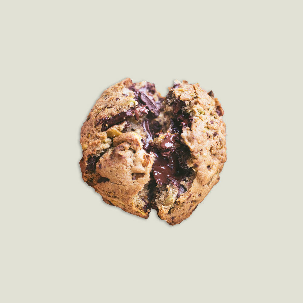 Image of a Brown Butter Pistachio Chocolate Chip Cookie being split in two.